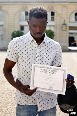 Mamoudou Gassama présente un certificat de courage et de dévouement à la sortie de l'Elysée après sa rencontre avec le président français Emmanuel Macron à Paris, le 28 mai 2018.