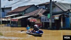 Warga memanfaatkan perahu sebagai alat transportasi saat banjir melanda Kabupaten Bandung, Jawa Barat (VOA/Teja Wulan).