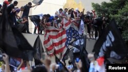 Para demonstran Mesir yang marah menurunkan bendera Amerika di Kedubes AS di Kairo dan merobek bendera itu, Selasa (11/9). 