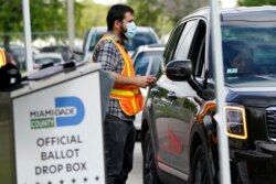 FILE - An election worker takes ballots from voters dropping them off at an official ballot drop box at the Miami-Dade County Board of Elections, in Doral, Fla., Oct. 26, 2020.