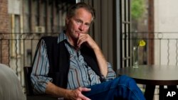 A burned vehicle is seen as wind blow small burning pieces of a tree caused by the Lake Hughes fire in Angeles National Forest, north of Santa Clarita, California.