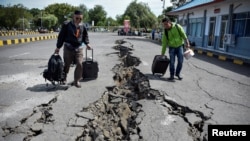 Warga berjalan di jalan yang rusak akibat gempa di Pelabuhan Kayangan, Lombok, 20 Agustus 2018. (Foto: Antara via Reuters)