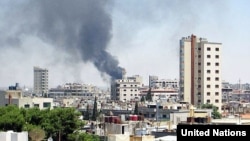 Smoke rises from buildings hit by shelling in Homs, Syria