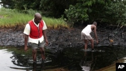 Des hommes marchent dans une nappe de pétrole près de la ville de Bodo dans la région riche en pétrole du Delta du Niger au Nigeria, le 10 juin 2010.