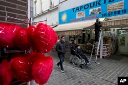 People pass a shop in the Molenbeek neighborhood of Brussels, March 19, 2016, where fugitive Salah Abdeslam was arrested after a four-month manhunt.
