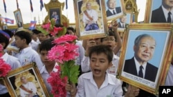 Pelajar di Kamboja memegang potret mantan Raja Norodom Sihanouk (kanan), putranya Raja Norodom Sihamoni, dan bunga dalam sebuah perayaan hari kemerdekaan di Phnom Penh.