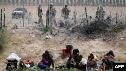 Para migran Amerika Tengah yang mencari suaka di AS diawasi oleh Garda Nasional Texas setelah mereka menyeberang dari kota Ciudad Juarez, Chihuahua, Meksiko, pada tanggal 4 Juni 2024.