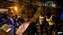 French police talk to migrants during an evacuation operation in Paris, Nov. 7, 2019. More than 1,000 migrants and homeless have settled in this area for months. 