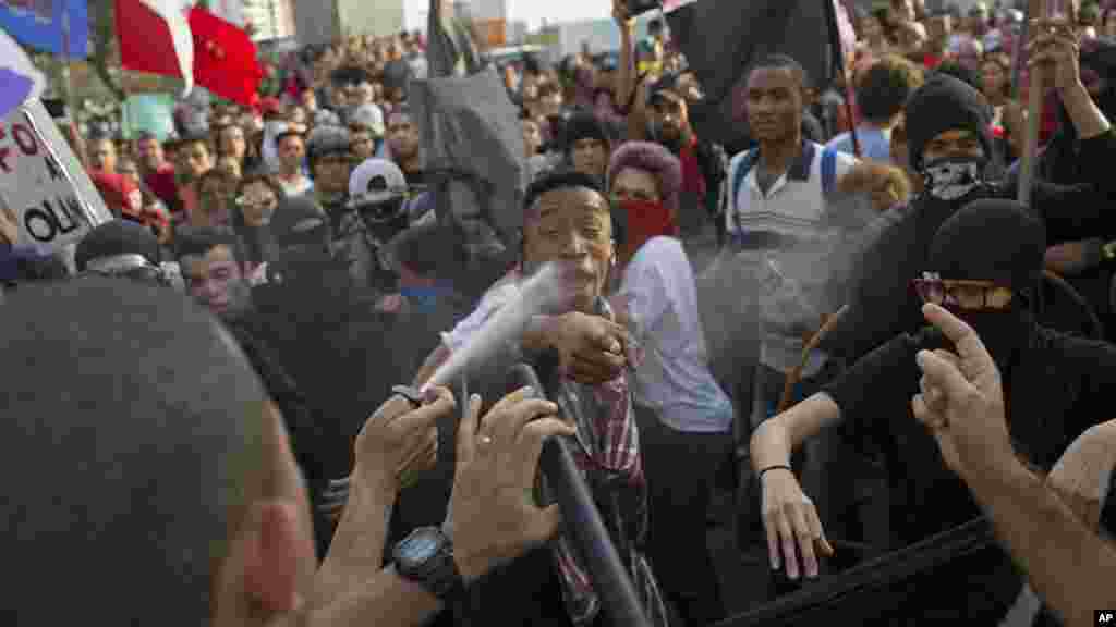 Un policier pulvérise une bombe de piment sur des manifestants qui protestent au passage de la flamme olympique, à Niteroi, Brésil, 2 août 2016.