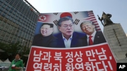 Sebuah poster bergambar Presiden Donald Trump (kanan), Presiden Korea Selatan Moon Jae-in dan Pemimpin Korea Utara Kim Jong Un (kiri), terpampang sebagai dukungan atas pertemuan puncak pemimpin dari dua negara Korea, di Seoul, Korea Selatan, 27 April 2018. 