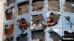 Workers clear broken glass from windows at a group of companies belonging to business tycoon Tawfeek Abdo Al-Raheem, which was damaged by fighting between Shi'ite Houthi rebels and government forces, in Sana'a, Sept. 28, 2014. 
