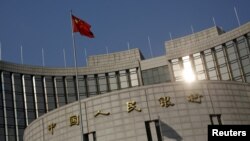 FILE - A Chinese national flag flies at the headquarters of the People's Bank of China, the country's central bank, in Beijing, Jan. 19, 2016. 