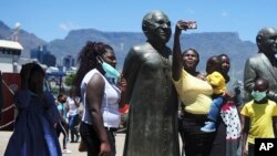 People take photos at a statue of Anglican Archbishop Desmond Tutu at the V&A Waterfront in Cape Town, South Africa, Dec. 26, 2021. 