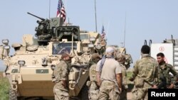 FILE - Kurdish fighters from the People's Protection Units (YPG) chat with members of U.S. forces in the town of Darbasiya next to the Turkish border, Syria, April 29, 2017.