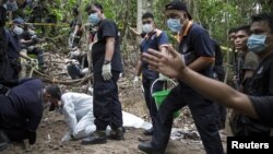 Polisi Malaysia dan pakar forensik menggali kuburan di Bukit Wang Burma di Malaysia utara dekat perbatasan Thailand, di mana ditemukan 139 jasad manusia (26/5).