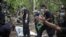 Policemen monitor as forensic experts dig out human remains near the abandoned human trafficking camp in the jungle close the Thailand border at Bukit Wang Burma in northern Malaysia May 26, 2015. Malaysian police forensic teams, digging with hoes and sho