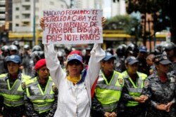 FILE - A woman holds a sign that reads: "Maduro gives oil to Cuba and people die of hunger. Enough. Country do not give up" during a protest in Caracas, Venezuela, Aug. 16, 2018.