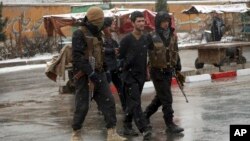 FILE - Afghan security personnel detain a suspect at the site of an attack on the Marshal Fahim military academy in Kabul, Afghanistan, Jan. 29, 2018. The Islamic State group claimed responsibility for the assault. 