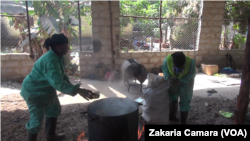 Mariam et l'une de ses employées mettent les plastiques dans la cuve, à Conakry, le 5 février 2019. (VOA/Zakaria Camara)