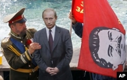RUSSIA – A man dressed up to resemble Russian Czar Nicholas II, left, sets up a cardboard cutout of Russian President Vladimir Putin and another man, behind the flag, holds a red flag with former Soviet leader Josef Stalin. Moscow, July 13, 2012