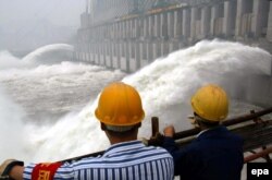 វិស្វករ​ចិន​ឈរ​មើល​ទឹក​ហូរ​ចេញ​ពី​ទំនប់​នៅ​ទីក្រុង Yichang ខេត្ត Hubei ប្រទេស​ចិន កាលពីថ្ងៃទី១០ ខែមិថុនា ឆ្នាំ២០០៣។