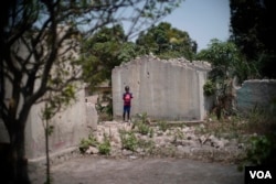 A young boy stands next to the shell of a home that was destroyed in the PK5 neighborhood of Bangui, February 2017. (Z. Baddorf/VOA)