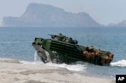 FILE - A U.S. Navy's amphibious assault vehicle with Philippine and U.S. troops on board storms the beach at a combined assault exercise at a beach facing one of the contested islands in the South China Sea known as the Scarborough Shoal in the West Philippine Sea Tuesday, April 21, 2015.