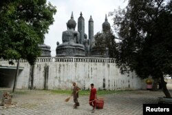 A Buddhist monk and a patient sweep the yard at Wat Thamkrabok monastery in Saraburi province, Thailand, Feb. 3, 2017.