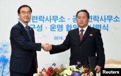 조명균 한국 통일부 장관과 리선권 북한 조국평화통일위원회(조평통) 위원장이 14일 남북 공동연락사무소 개소식에서 악수하고 있다.