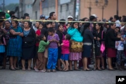 Neighbors stand outside a temporary resting place for the dead near Volcan de Fuego or Volcano of Fire in Alotenango, Guatemala, Sunday, June 3, 2018.