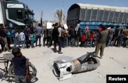 FILE - A boy stands next to the remains of a missile, in Douma, near Damascus, Syria, April 16, 2018.