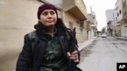 FILE - Kurdish fighter Pervin Kobani rides in the back of a pickup truck through Kobani, Syria. Female fighters have been integral to the war efforts.