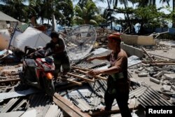 Villagers push a motorcycle on debris after an earthquake hit Lombok Island in Pemenang, Indonesia, Aug. 6, 2018.