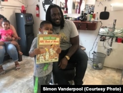 Trey Hopkins, a Cincinnati Bengals football player, reads with Kevelle Boyd at Korporate Kuts Barbershop in Cincinnati, Ohio. Simon Vanderpool started Books, Barbers and Ballers, to bring professional athletes into the reading and mentoring program.