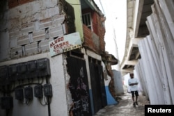 FILE - A for rent sign hangs alongside a bridge of the Transolimpica BRT, an express road built through the Vila Uniao favela of Rio de Janeiro to join two Rio 2016 Olympic venues, Aug. 12, 2016.