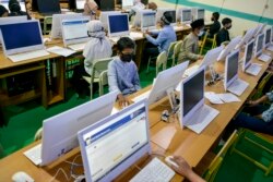 Para siswa mengenakan masker dan menjaga jarak untuk mencegah penularan virus corona, sedang melaksanakan tes berbasis komputer di sebuah sekolah menengah pertama di Banda Aceh, Aceh, 10 Juni 2020. (Foto: AFP)