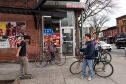FILE - High school students hang out on a Brooklyn street corner, Friday, March 20, 2020 in New York. The city's public schools are closed due to the coronavirus. (AP Photo/Mark Lennihan)