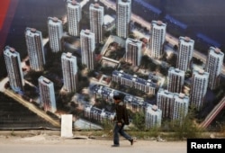 人走过天津滨海新区一处新居民楼群的墙壁（2015年10月18日）