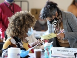 Fulton County election workers examine ballots while vote counting, at State Farm Arena on November 5, 2020, in Atlanta, Georgia. (Photo by Tami Chappell / AFP)