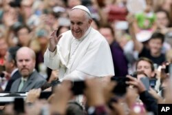 FILE - Pope Francis acknowledges faithful as he parades on his way to celebrate Mass in Philadelphia, Sept. 27, 2015.