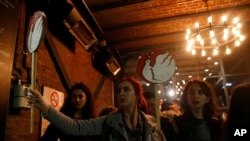 Protesters hold placards as they take cover at a shop after Turkish police fired tear gas on Istiklal, the main shopping street, in Istanbul, during International Women's Day, March 8, 2019.