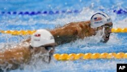 United States' Michael Phelps, top, and Singapore's Joseph Schooling compete during a men's 100-meter butterfly heat during the swimming competitions at the 2016 Summer Olympics, Aug. 11, 2016, in Rio de Janeiro, Brazil.