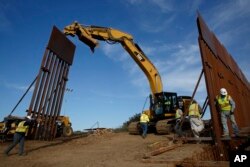 FILE - Construction crews install new border wall sections, Jan. 9, 2019, seen from Tijuana, Mexico.