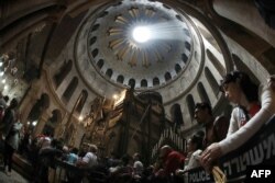 A picture taken with a fisheye lens shows Christian worshippers praying inside the Church of the Holy Sepulchre as rays of sunlight come through the top rotunda in Jerusalem’s Old City during the Good Friday procession on March 25, 2016.