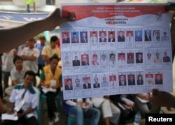 FILE - People watch as electoral officials show ballot papers during vote counting at a polling station in Jakarta April 9, 2014.