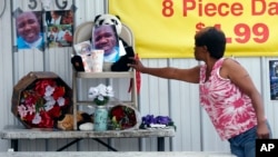 A woman touches a makeshift memorial for Alton Sterling, outside a convenience store in Baton Rouge, Louisiana, July 6, 2016. Sterling was shot and killed by police outside the store.