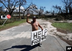 Michael Williams, 70, waves to passing motorists while looking for food and water as downed trees prevent him from driving out of his damaged home with his family in the aftermath of Hurricane Michael in Springfield, Fla., Oct. 11, 2018.