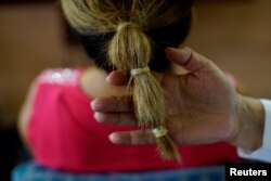 Penata rambut Sandra Hernandez memperlihatkan kondom-kondom yang digunakan untuk mengikat rambut di salonnya, di Havana, Kuba, 16 Mei 2018.