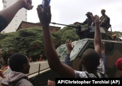 People begin to gather around a military vehicle in Harare Saturday, Nov. 18, 2017, demonstrating for the ouster of 93-year-old president Robert Mugabe who is virtually powerless and deserted by most of his allies.