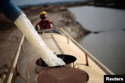 FILE - A worker fills a truck with water pumped from one of the canals being built to divert water from the Sao Francisco river for use in four drought-plagued states, near the city of Mauriti, Ceara state, Brazil, Jan. 28, 2014.